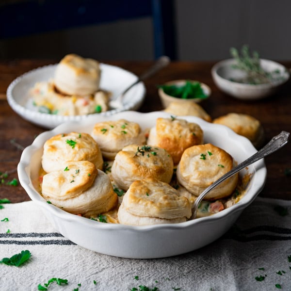 Square side shot of easy chicken pot pie recipe with biscuits on a wooden dinner table