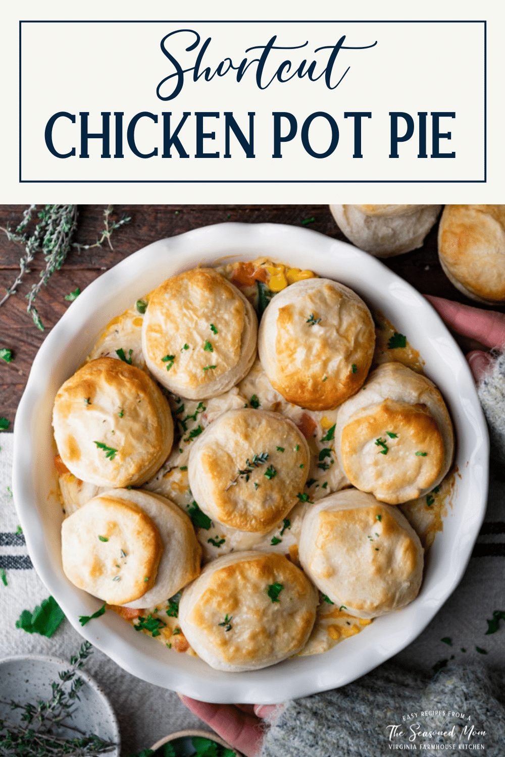 Overhead shot of hands holding a plate of chicken pot pie with biscuits and text title box at top
