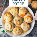 Overhead shot of hands serving chicken pot pie with biscuits with text title overlay