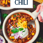 Spoon in a bowl of slow cooker chili with text title overlay