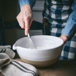 Whisking dry ingredients in a large white bowl.