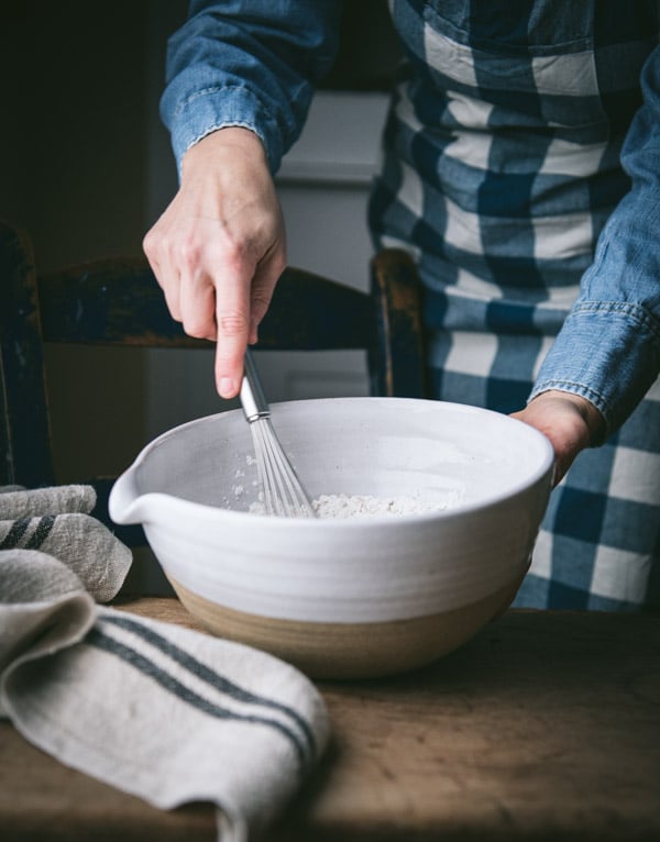 Whisking dry ingredients in a large white bowl.