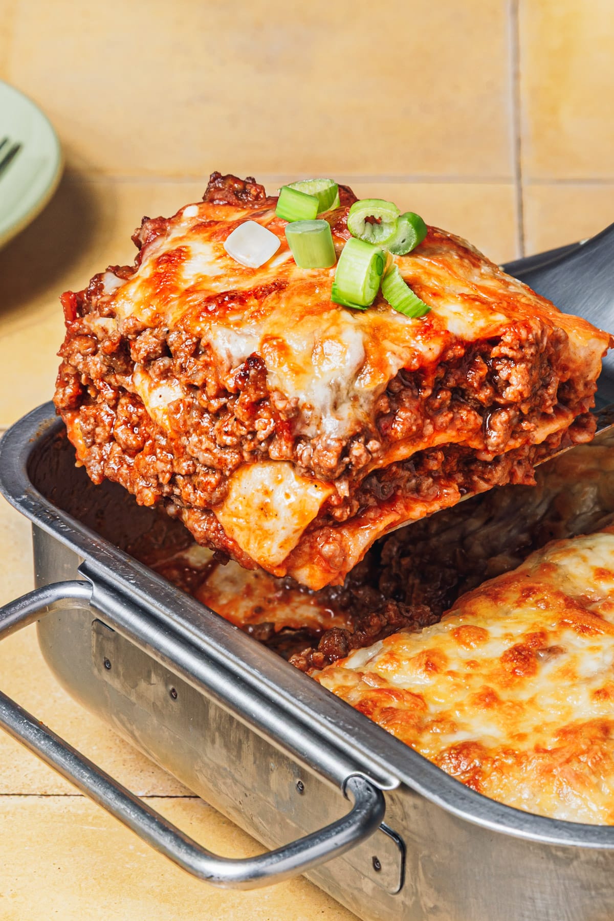 Side shot of a square of easy beef enchilada casserole on a serving spatula.
