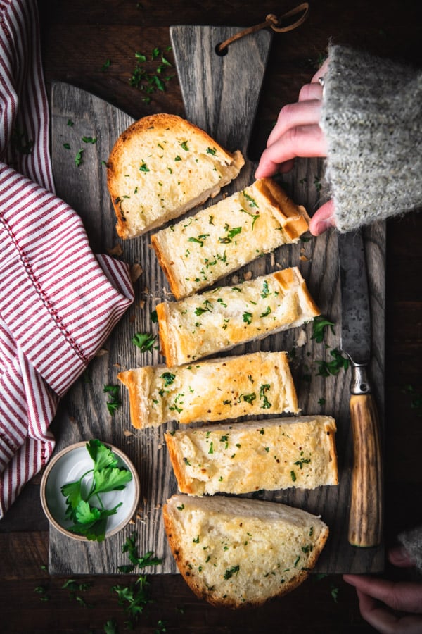 Overhead shot of hand picking up a piece of homemade garlic bread