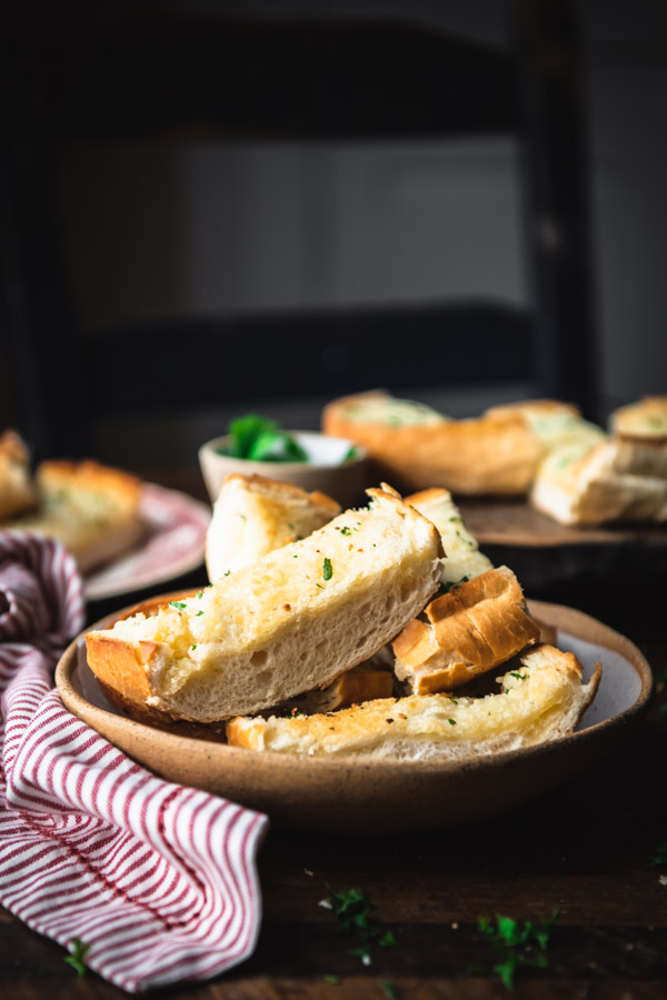 Side shot of a bowl of homemade garlic bread on a dinner table