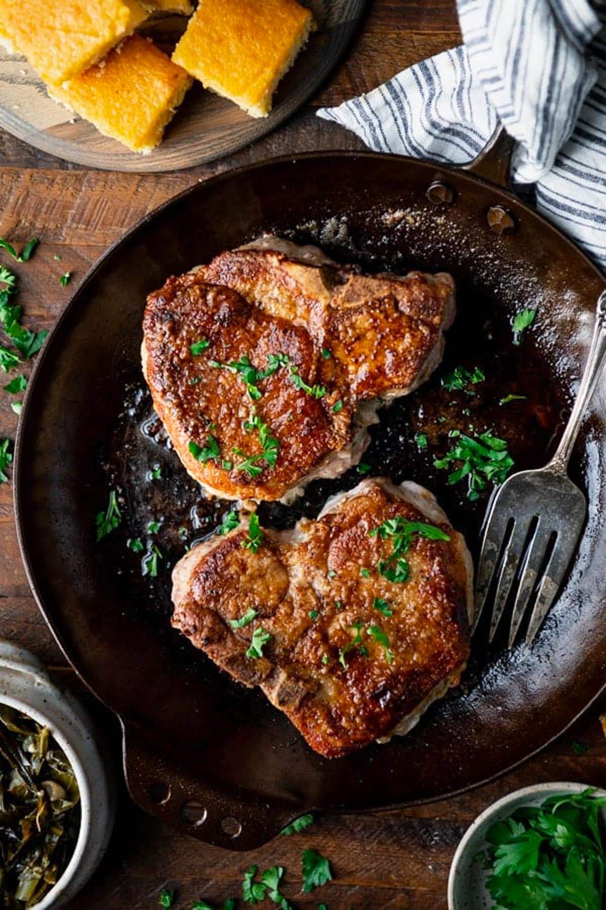 Overhead image of thick and juicy pan fried pork chops with parsley garnish.