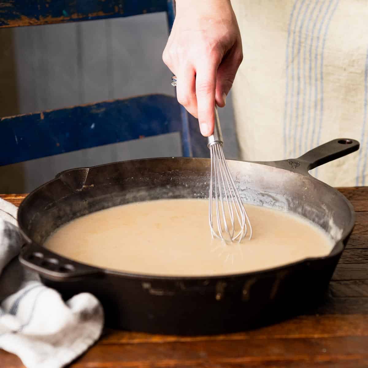 Process shot showing how to make Swedish meatball gravy in a skillet.