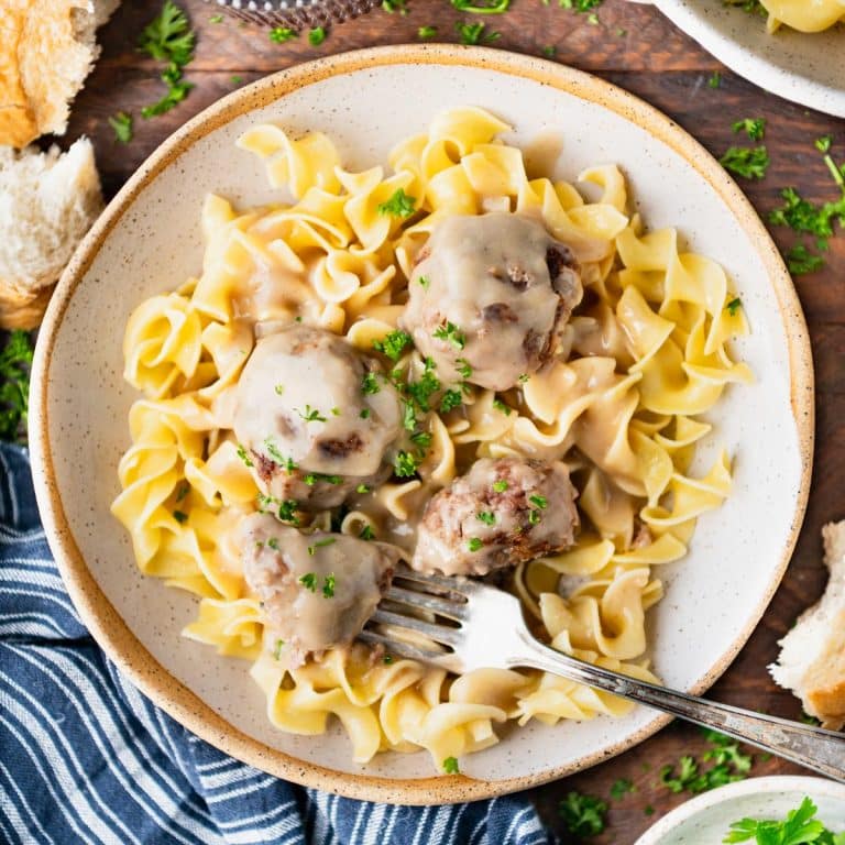 Square overhead shot of the best Swedish meatballs recipe served on a wooden dinner table.