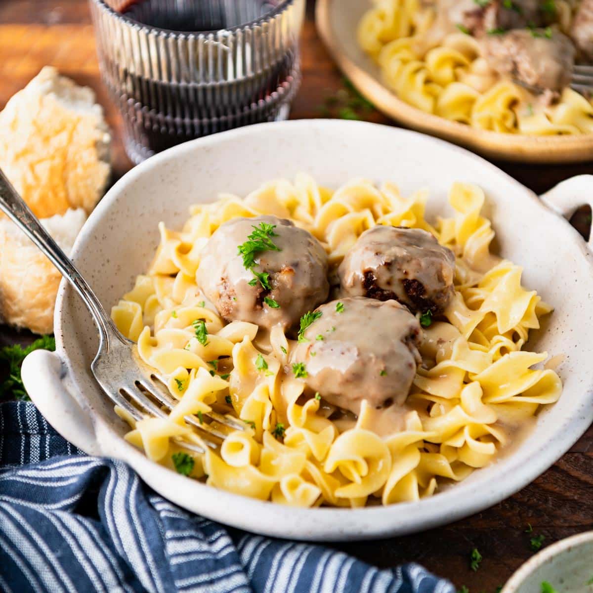 Square side shot of a bowl of Swedish meatballs with egg noodles.