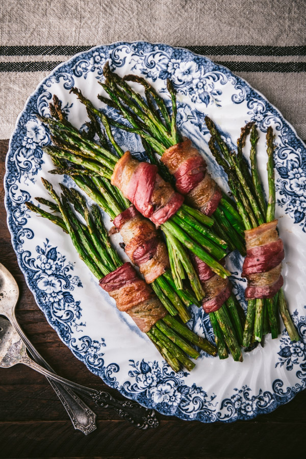 Bundles of bacon wrapped asparagus on a blue and white tray
