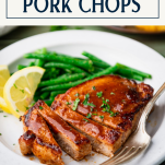 Sliced baked bbq pork chops on a white plate with text title box at top