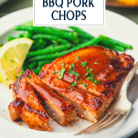 Close up shot of sliced baked bbq pork chops on a plate with text title overlay