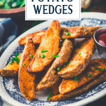 Side shot of crispy potato wedges on a plate with text title overlay