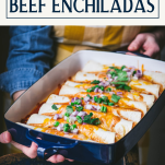 Hands holding a pan of the best beef enchilada recipe with text title box at top