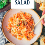 Hands eating a bowl of carrot salad with a fork and text title overlay
