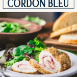 Side shot of a plate of easy chicken cordon bleu on a plate with salad and text title box at top