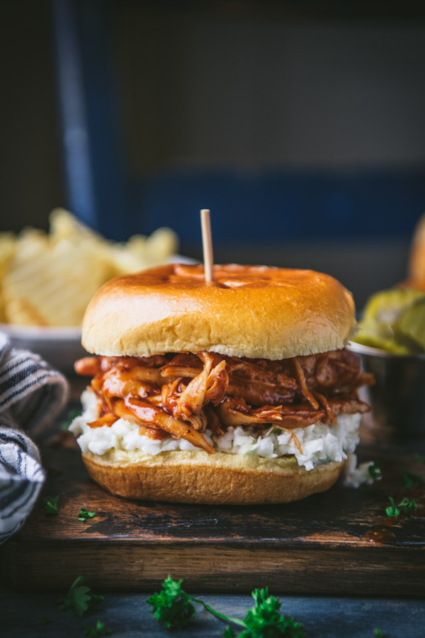 A pulled BBQ chicken sandwich made with a brioche hamburger bun, juicy pulled chicken, and creamy coleslaw.