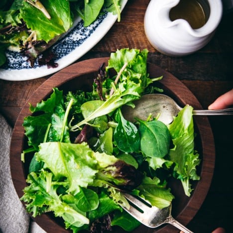 Hands tossing a salad with mustard vinaigrette