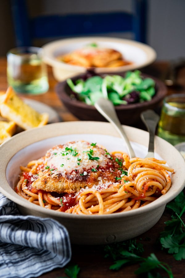 Close side shot of a bowl of the best easy chicken parmesan recipe on a dinner table.