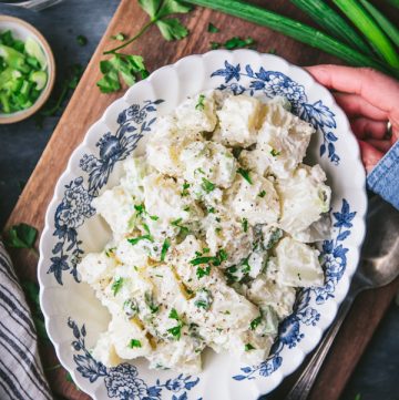 Overhead shot of hands holding a blue and white bowl of the best potato salad recipe