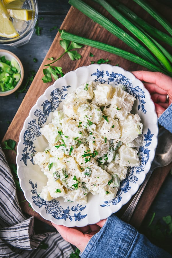 Overhead shot of hands holding a blue and white bowl of the best potato salad recipe
