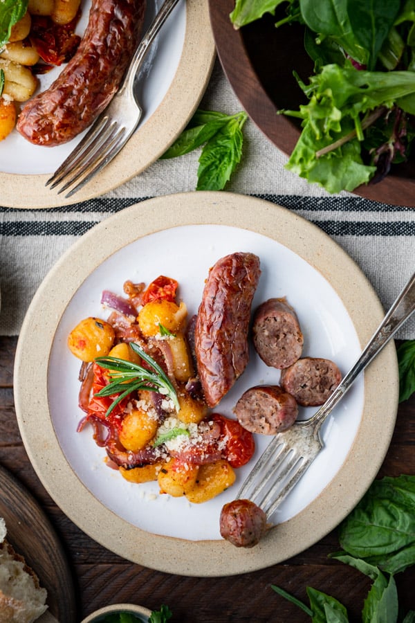 Close overhead image of a fork on a plate of Italian sausage and crispy baked gnocchi