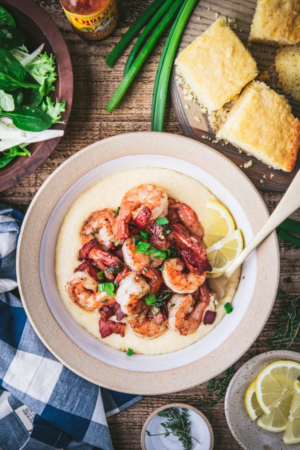 Overhead shot of a bowl of Cajun shrimp and grits on a wooden table