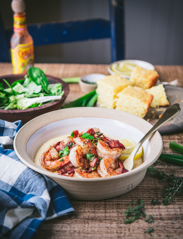Side shot of a bowl of the best shrimp and grits recipe on a wooden table