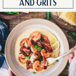 Overhead shot of hands eating a bowl of the best shrimp and grits recipe with text title box at top