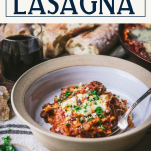 Side shot of skillet lasagna in a white dish with text title box at top