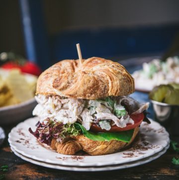 Close up side shot of the best Southern chicken salad recipe on a croissant with a side of potato chips