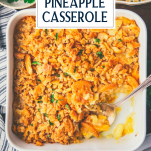 Close overhead shot of pineapple casserole with a serving spoon and text title overlay