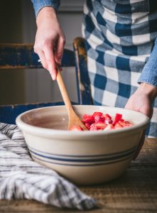 Stirring strawberries and sugar in a bowl