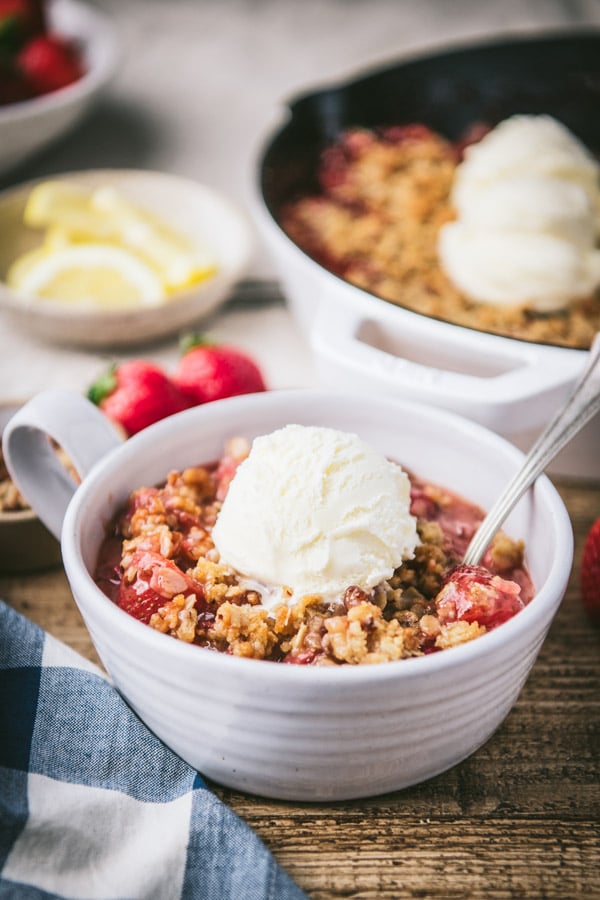 Side shot of strawberry crisp in a white bowl