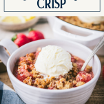 Side shot of a bowl of strawberry crisp with text title box at top