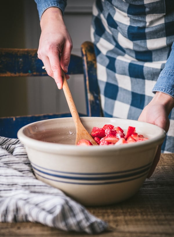 Stirring strawberries and sugar in a bowl