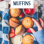 Hands reaching for strawberry muffins on a tray with text title overlay