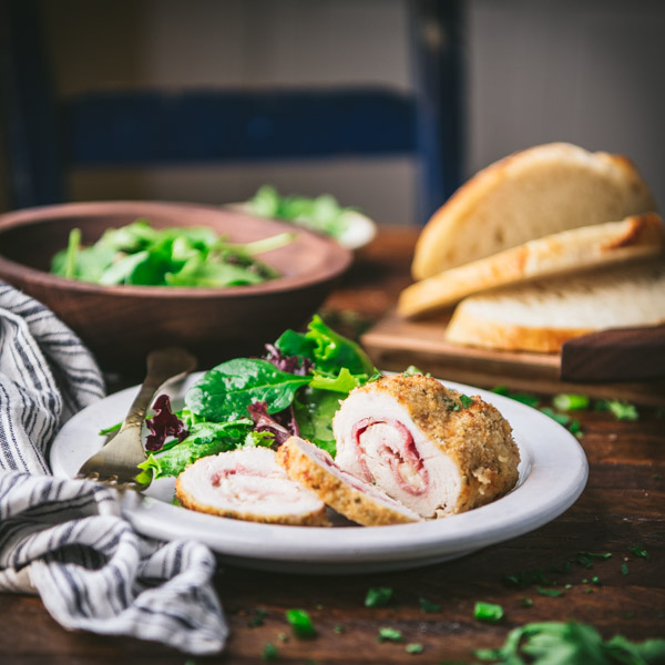 Plate of sliced chicken cordon bleu on a white plate with salad