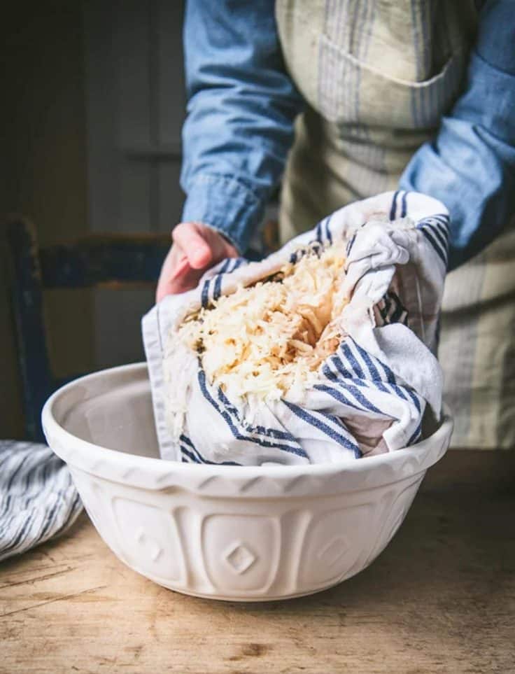 Squeezing grated potatoes dry in a dish towel.