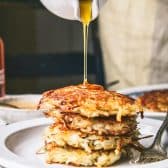 Drizzling syrup over a stack of great grandmother's potato pancakes recipe.
