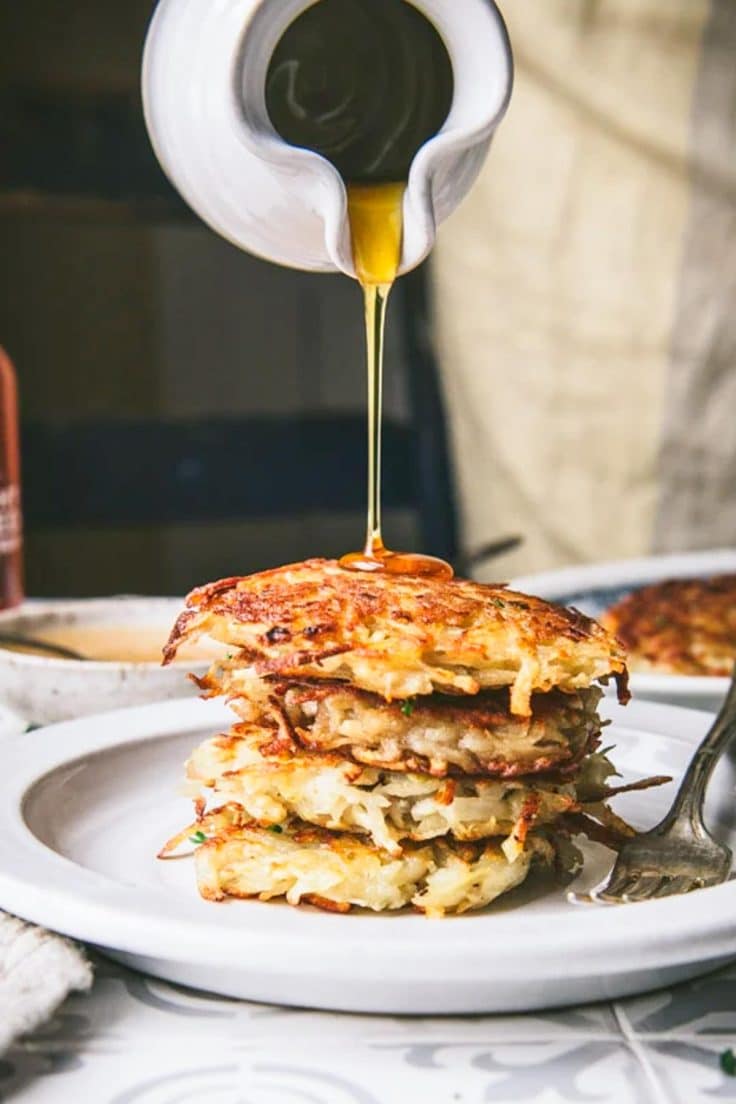 Drizzling syrup over a stack of great grandmother's potato pancakes recipe.