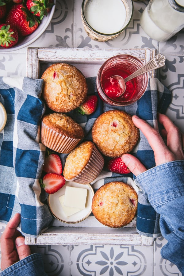 Overhead shot of a hands reaching for a tray of strawberry muffins