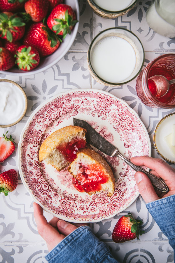 Overhead shot of a red and white vintage plate with a strawberry muffin and strawberry jam