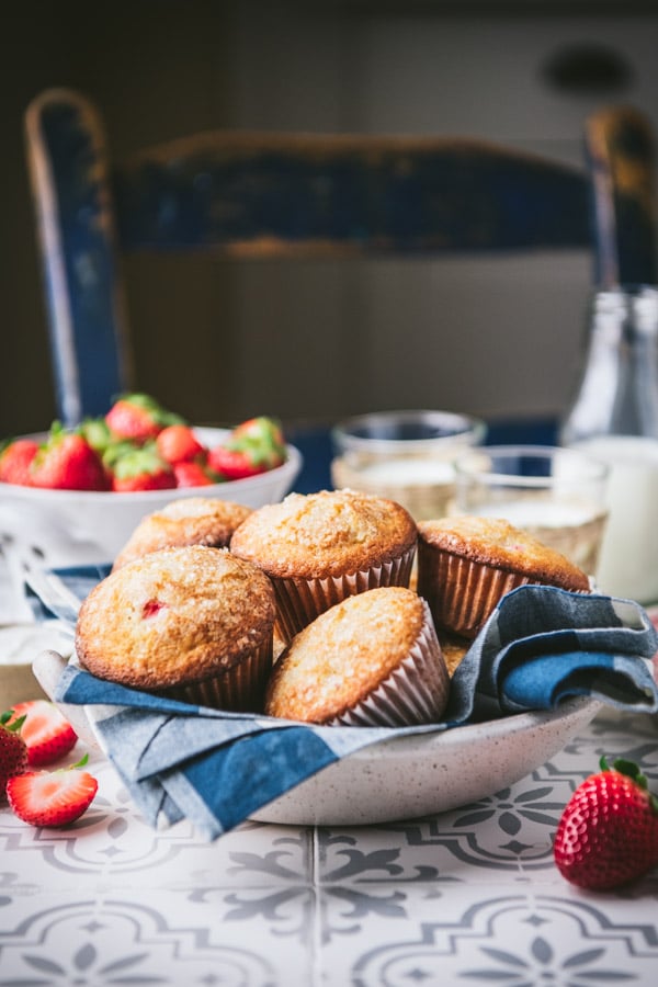 Side shot of a bowl of strawberry muffins on a table
