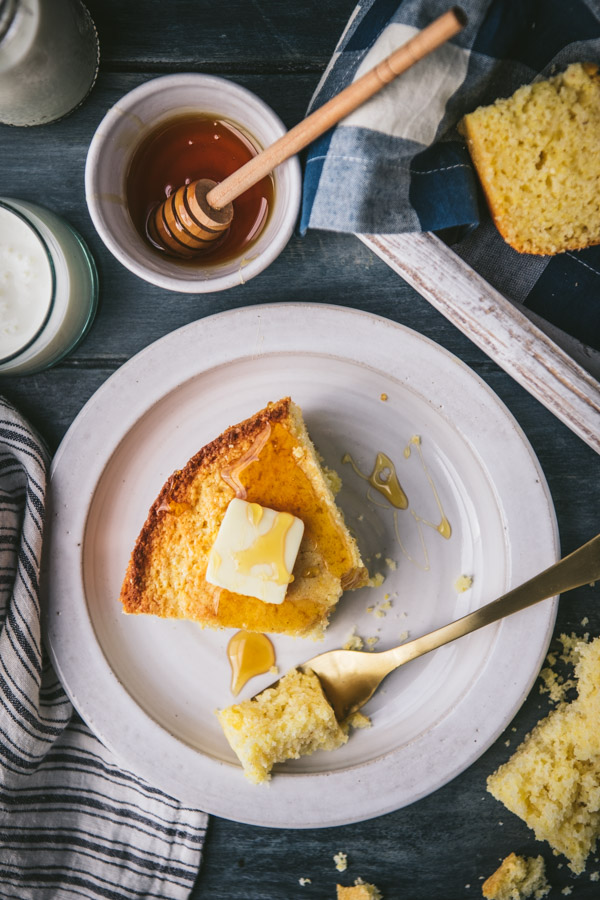 Close overhead shot of a white plate with sweet cornbread and butter and honey