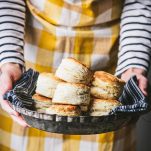 Hands holding a pan of buttermilk biscuits