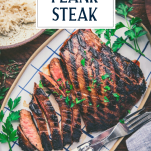 Sliced grilled marinated flank steak on a blue and white tray with text title overlay