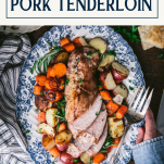 Overhead image of a sheet pan pork tenderloin with vegetables and potatoes and text title box at top
