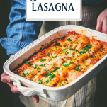 Side shot of vegetarian lasagna with spinach in a white dish with text title overlay