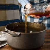 Pouring broth into a Dutch oven.